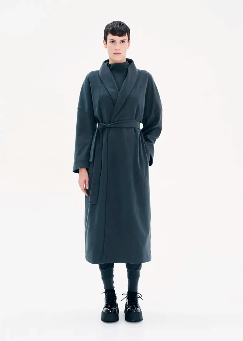 A model wearing a gray coat with a belt, featuring a buttoned front and a flowing fit.