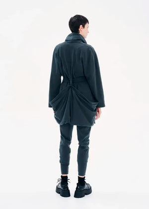 A model wearing a gray coat with a belt, featuring a buttoned front and a flowing fit.