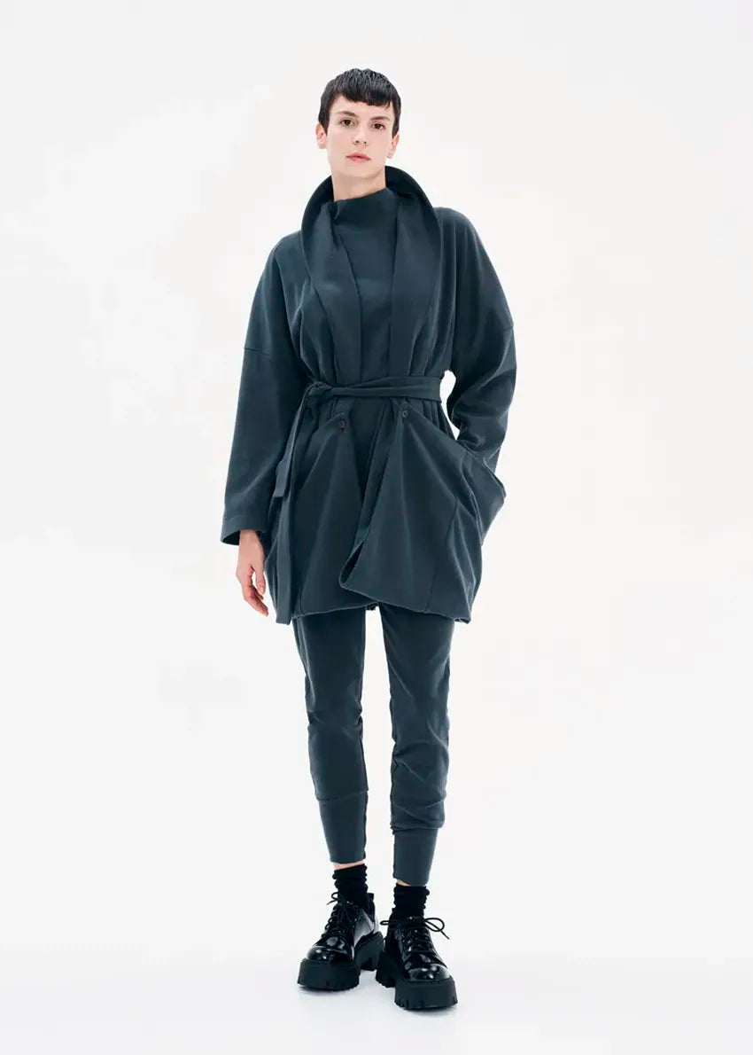 A model wearing a gray coat with a belt, featuring a buttoned front and a flowing fit.