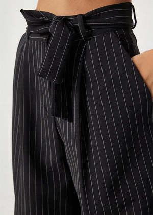 Close-up of black pants with vertical stripes and a tie-waist detail.