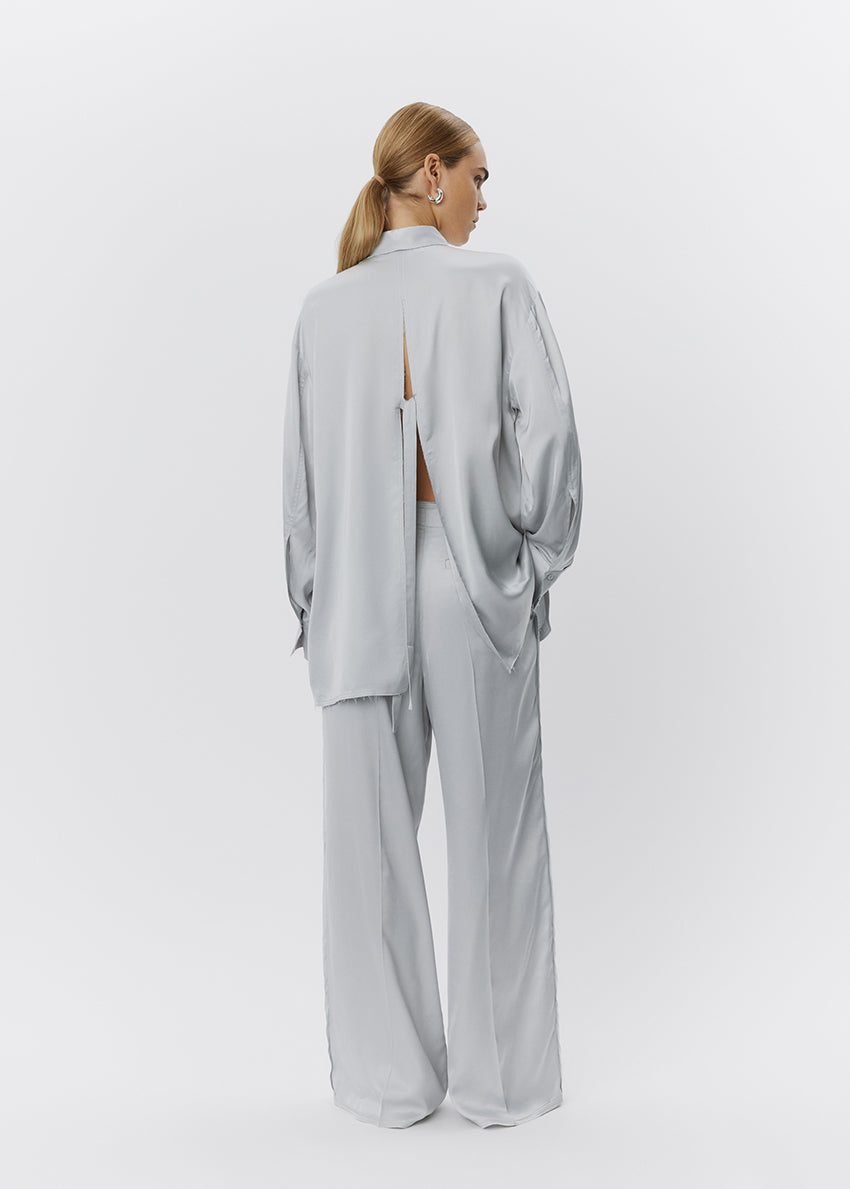 Woman wearing a light gray outfit with a cutout design on a white background