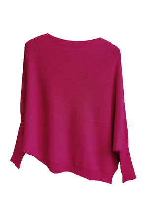 A fire brick, asymmetrical hemline sweater with fitted sleeves that flare out into a poncho-like shape