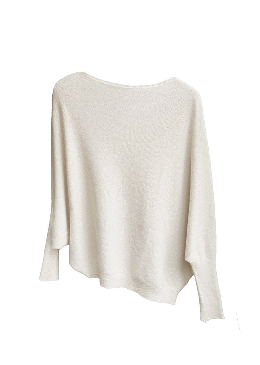 A ivory, asymmetrical hemline sweater with fitted sleeves that flare out into a poncho-like shape