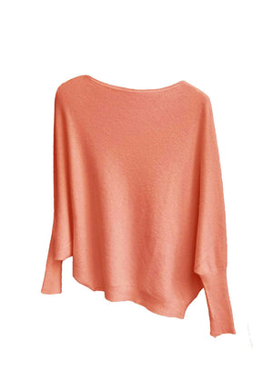 A salmon, asymmetrical hemline sweater with fitted sleeves that flare out into a poncho-like shape