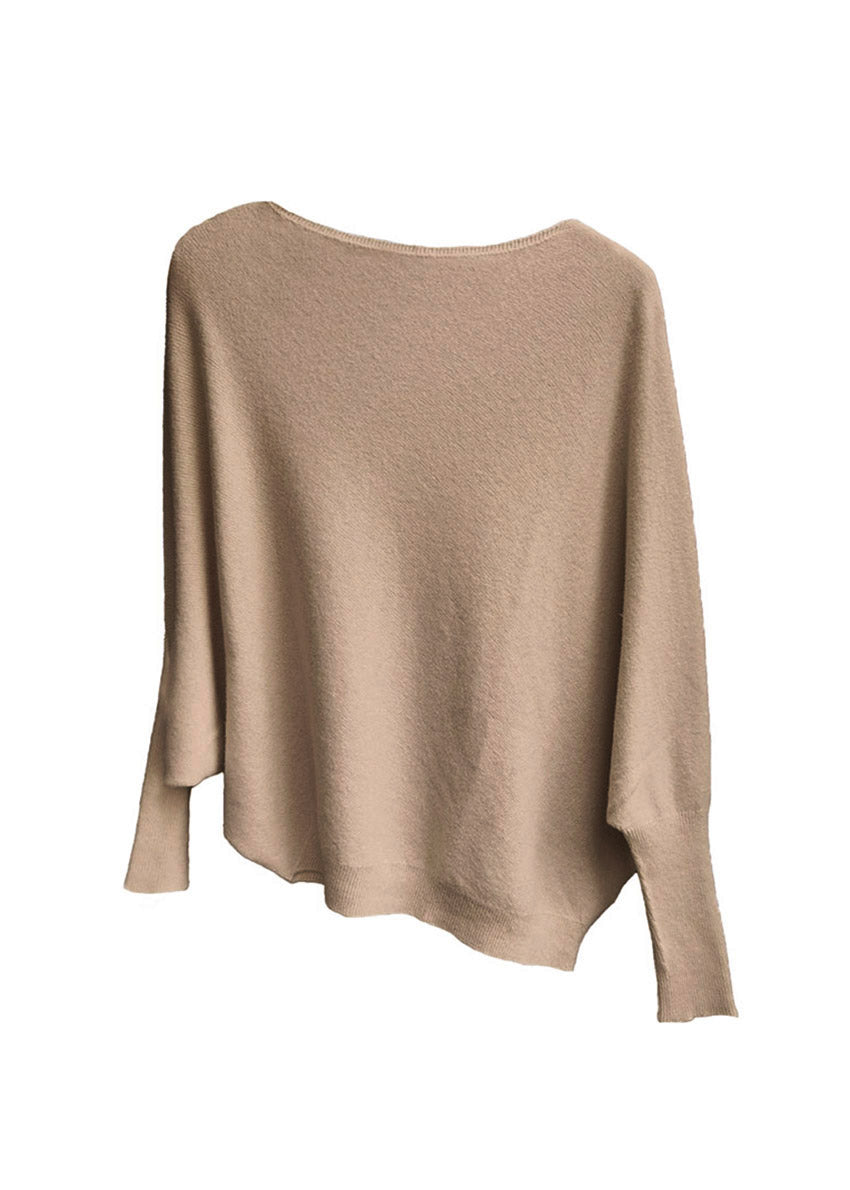 A tan, asymmetrical hemline sweater with fitted sleeves that flare out into a poncho-like shape