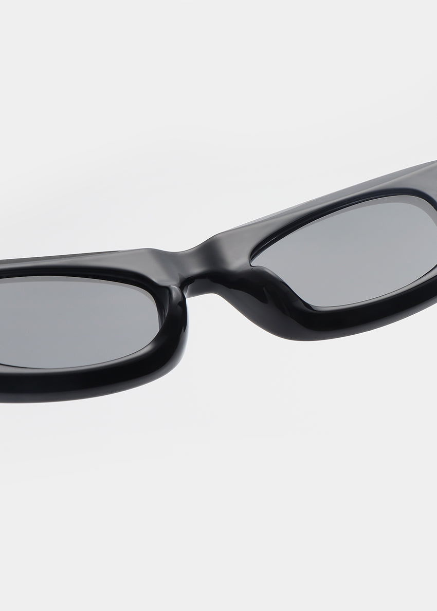 Black sunglasses with gray lenses on a light gray background