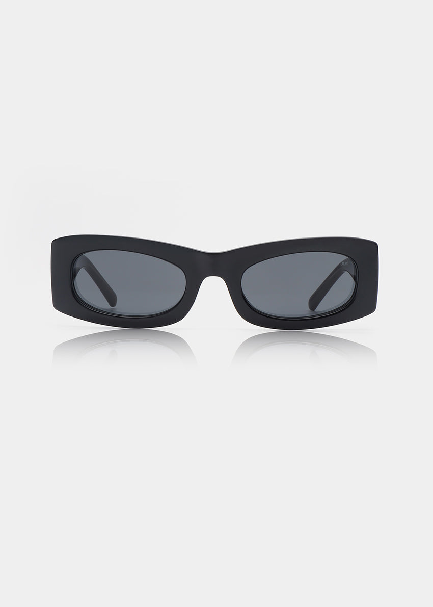 Person wearing black sunglasses and a black outfit against a plain background