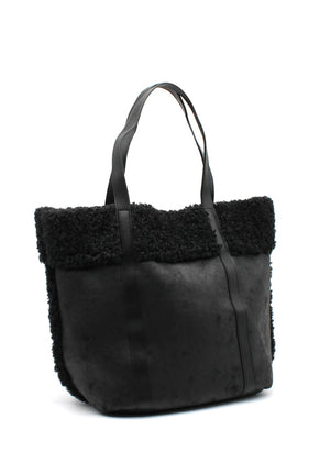 A black suede tote bag with faux shearling trim, sturdy handles, and a spacious design.