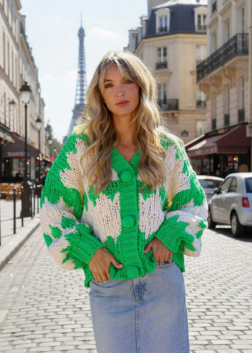 Woman wearing a green and white patterned cardigan in Paris with the Eiffel Tower in the background.