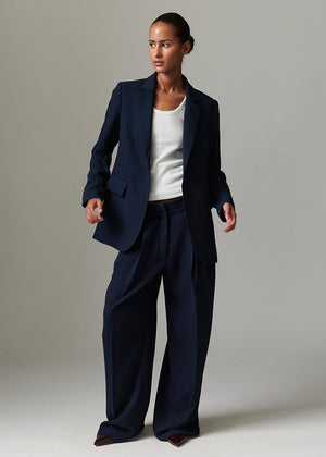 Woman wearing a navy suit with a white shirt on a plain background