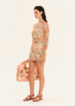 Woman wearing a floral dress holding a matching bag on a white background
