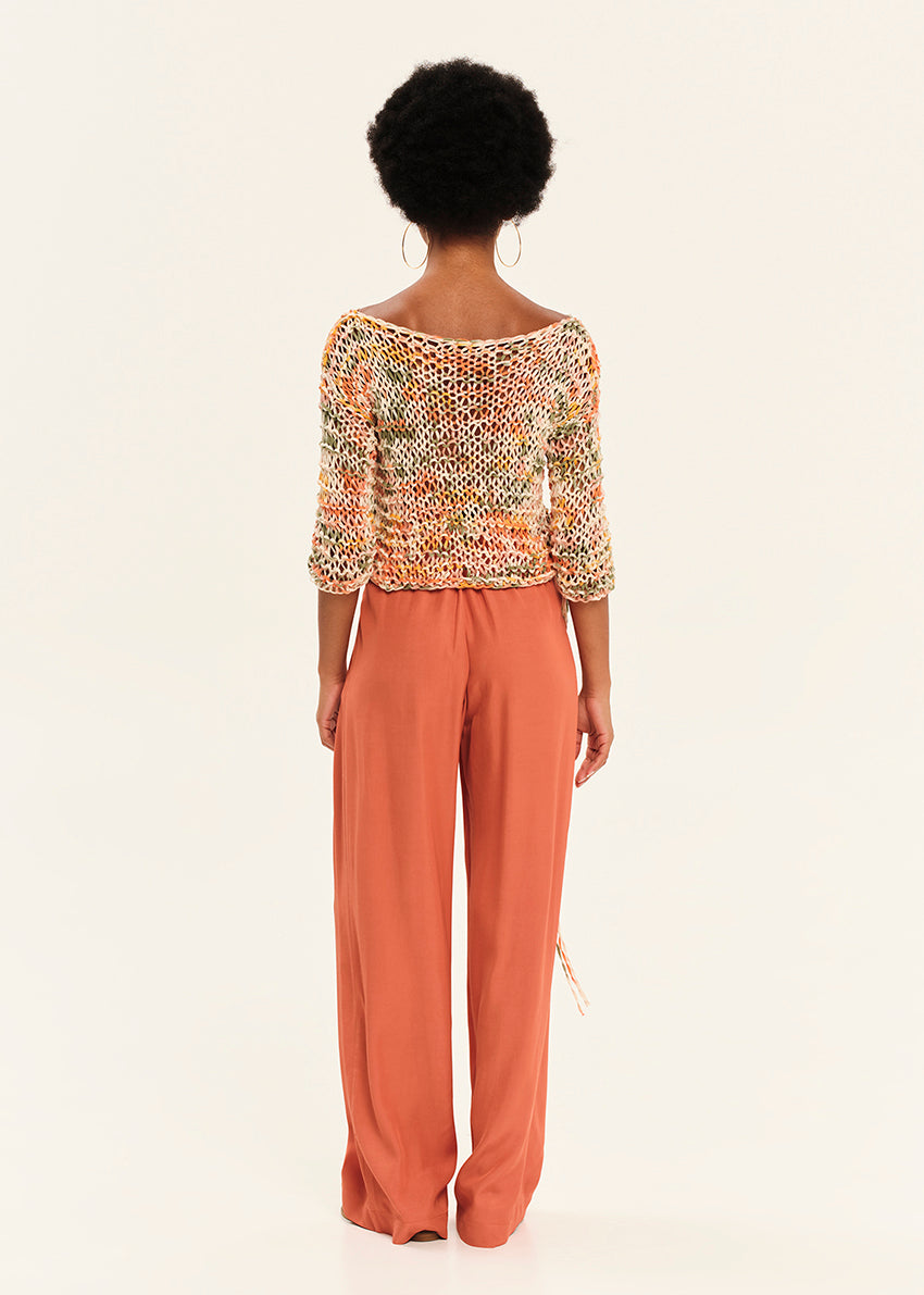 Person wearing a patterned top and wide-leg pants on a white background