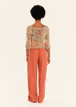 Person wearing a patterned top and wide-leg pants on a white background