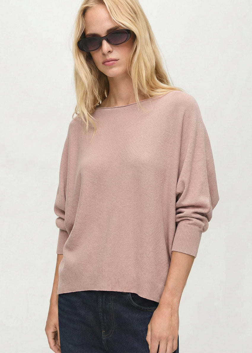 Woman wearing a tan sweater and sunglasses on a white background