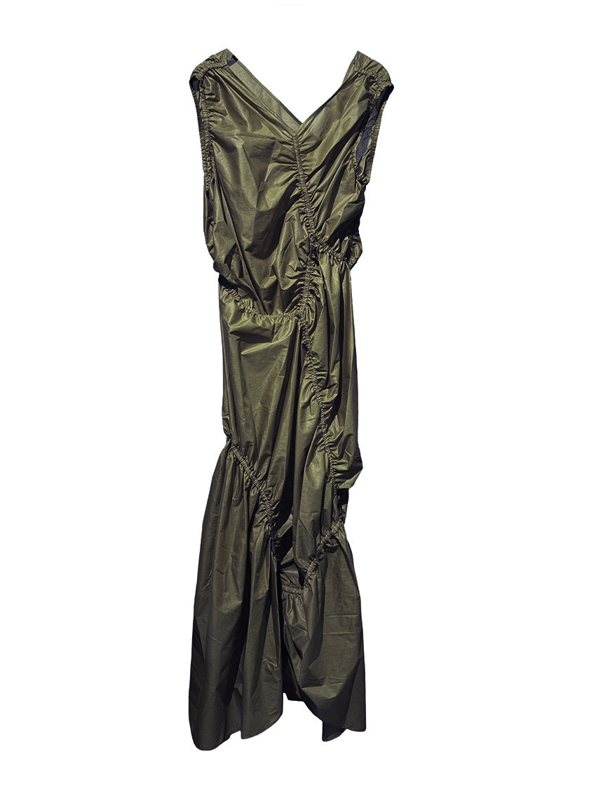 A long sleeveless asymmetrical green dress with a deep V neckline, featuring diagonal seams and gathering on all sides, modeled by a woman standing against a white background.