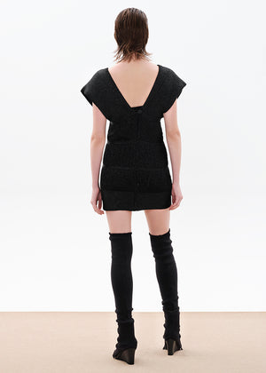A comfy fit that is close to the silhouette, it is sleeveless with lowered cap-style shoulders, its design has layered strands that are connected with fringes, it is lined with elastic tulle, it closes at the back with a button of the same yarn