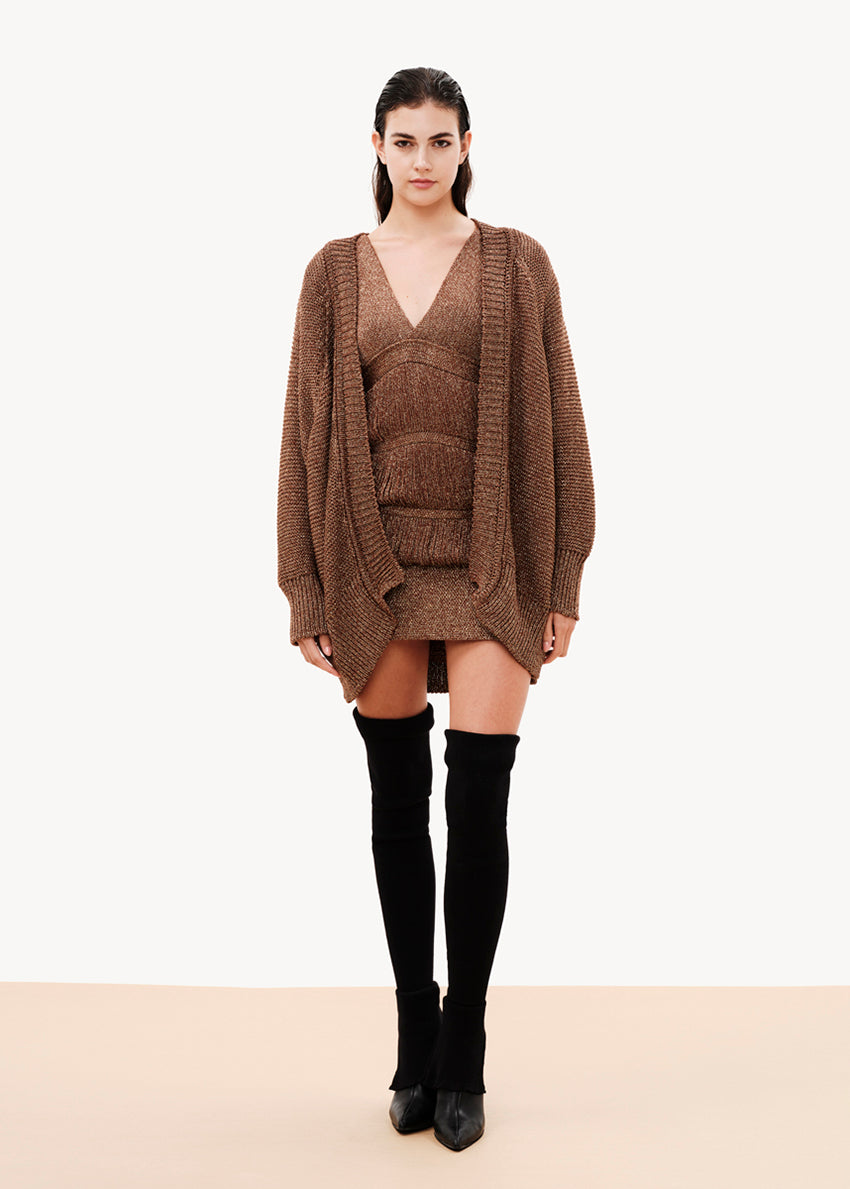 A comfy fit that is close to the silhouette, it is sleeveless with lowered cap-style shoulders, its design has layered strands that are connected with fringes, it is lined with elastic tulle, it closes at the back with a button of the same yarn