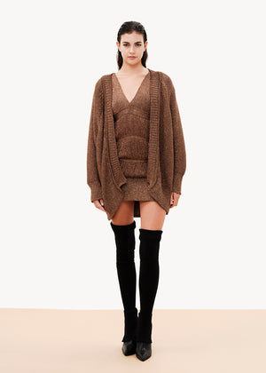 A comfy fit that is close to the silhouette, it is sleeveless with lowered cap-style shoulders, its design has layered strands that are connected with fringes, it is lined with elastic tulle, it closes at the back with a button of the same yarn