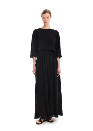 A model wearing a maxi high waisted black skirt with side cut-outs, paired with a matching top.