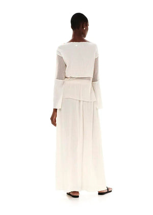 A model wearing a white high-waisted maxi skirt with textured cotton and side cut-outs, paired with a white top.