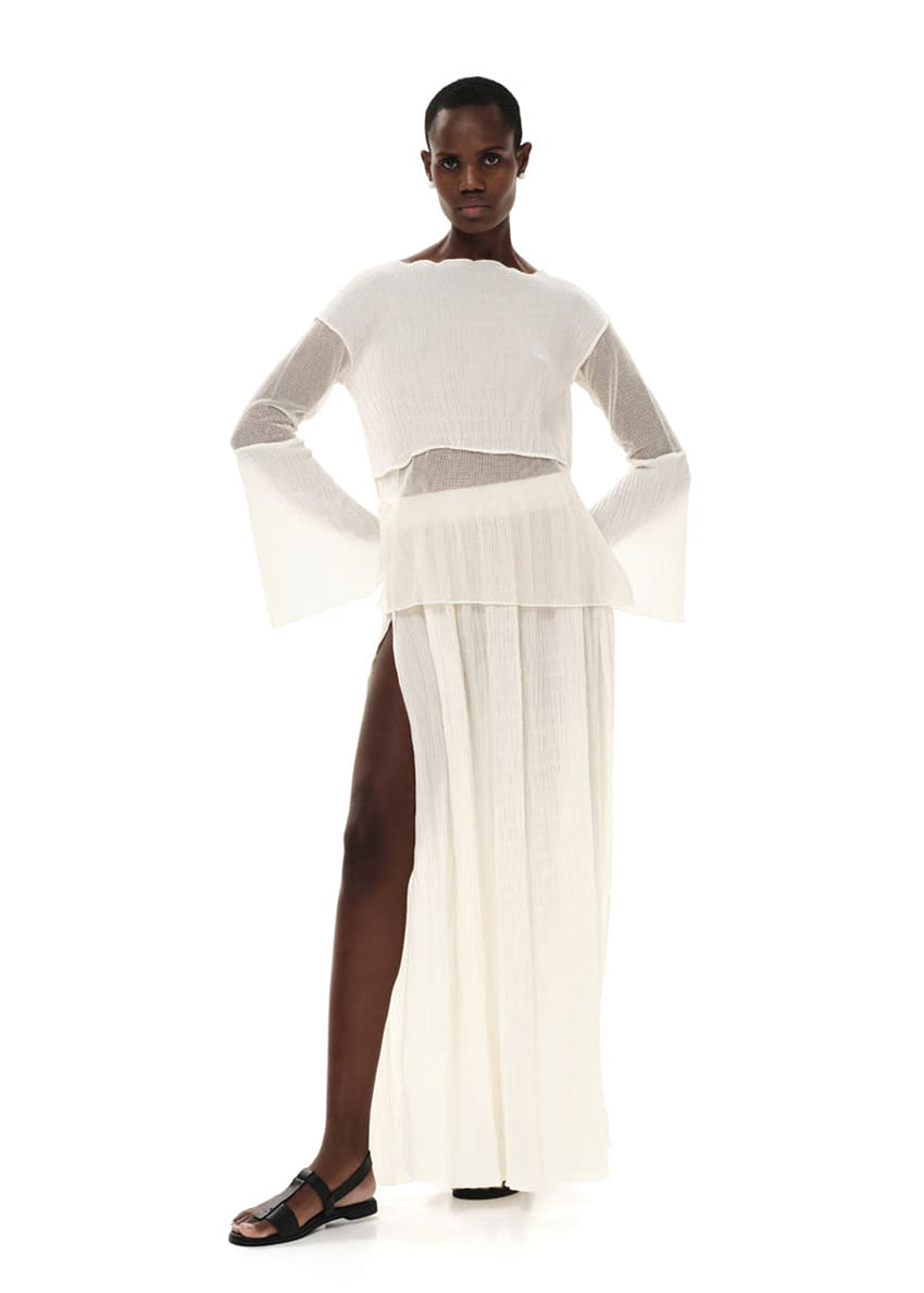 A model wearing a maxi high waisted black skirt with side cut-outs, paired with a matching top.