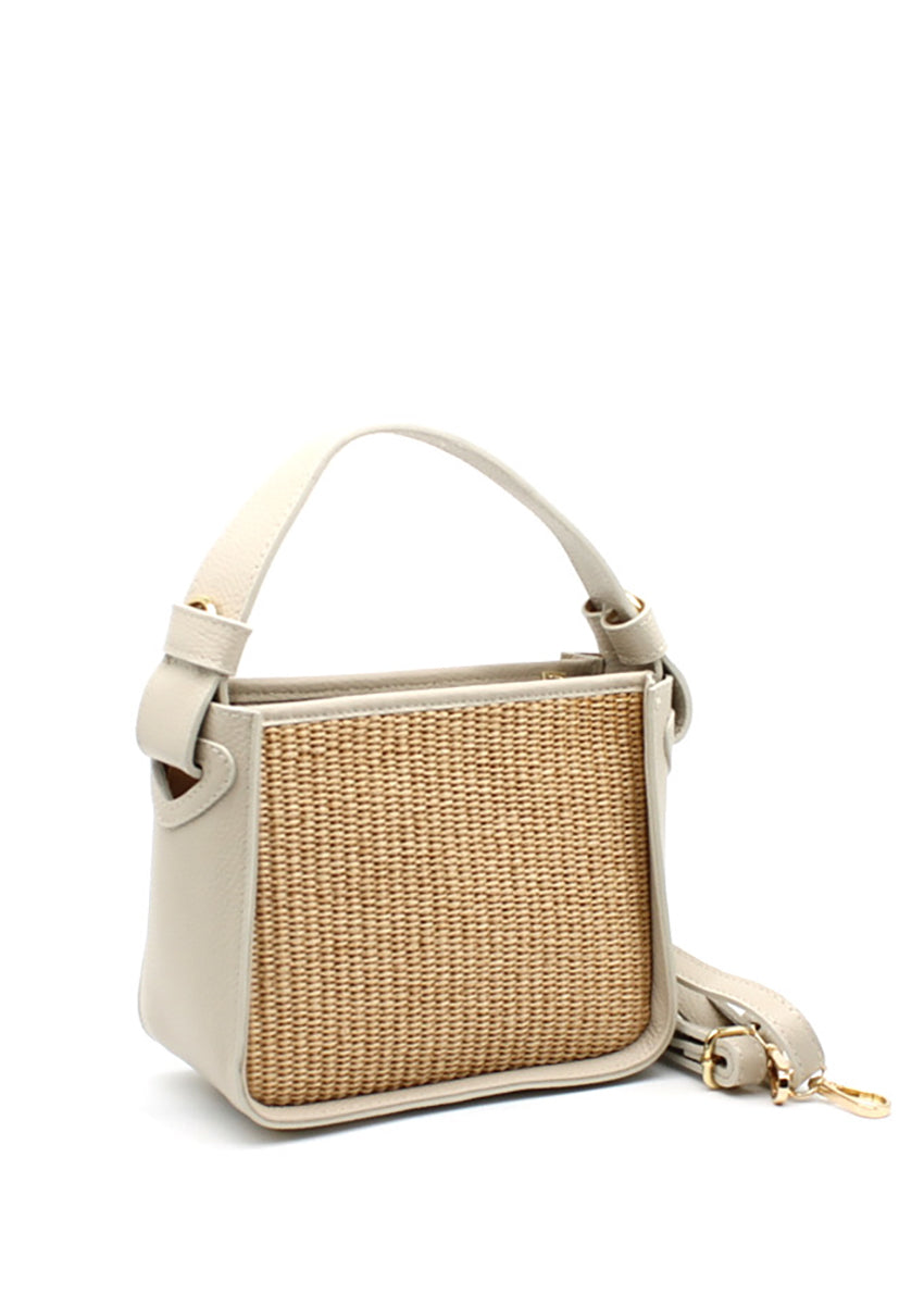 A beige handbag with a natural woven panel and leather accents, featuring an adjustable strap and sturdy handle.