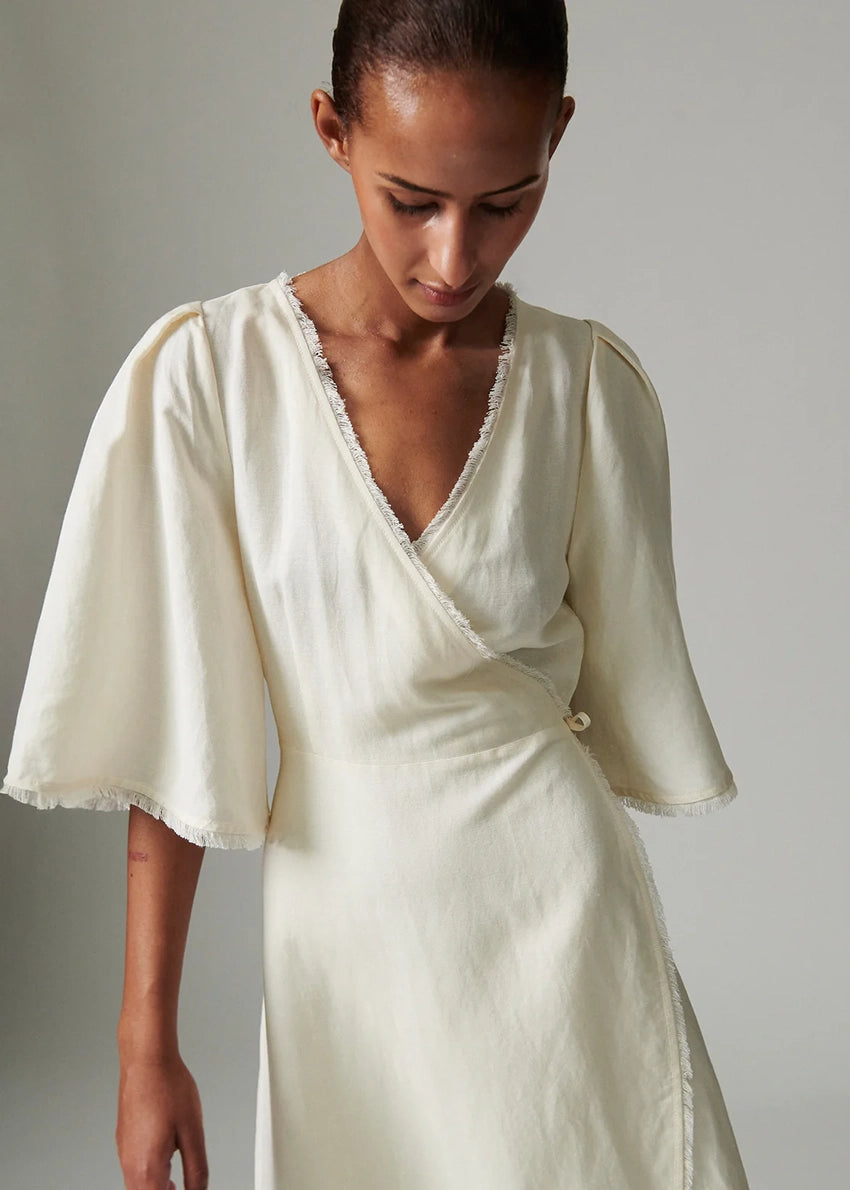 Woman wearing a white dress with puffed sleeves against a plain background