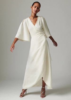 Woman wearing a white dress with bell sleeves against a plain background
