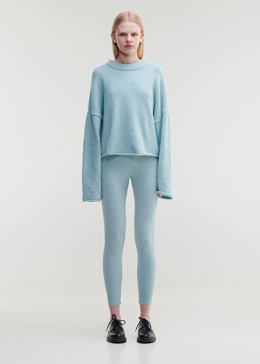A person wearing a wide crew neck, knitted top in light blue color.