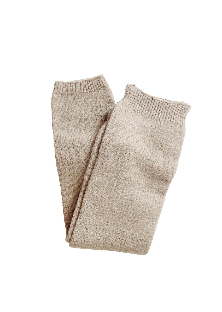 A woman wearing black sunglasses and a black off-shoulder top, paired with light gray armwarmers.