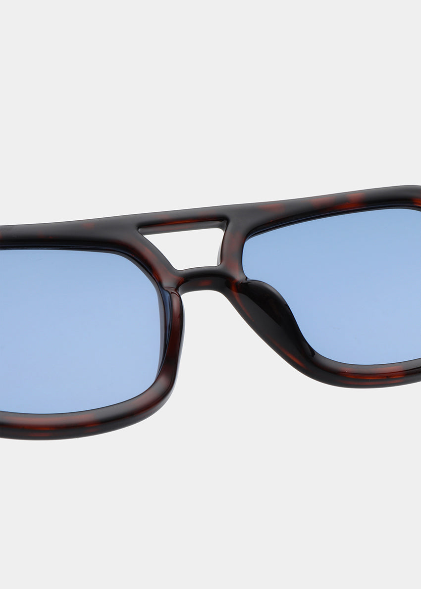 Sunglasses with blue lenses and tortoiseshell frame on a light gray background