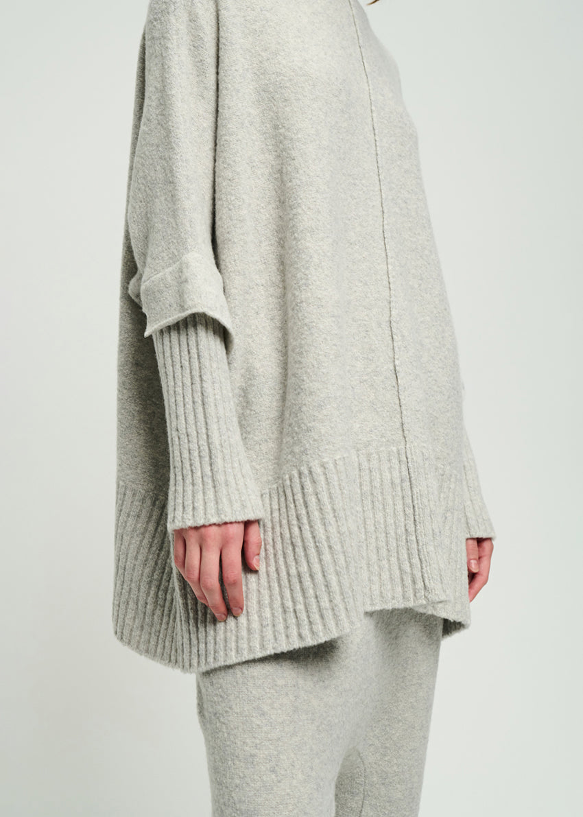 Light gray knit sweater worn by a person on a white background