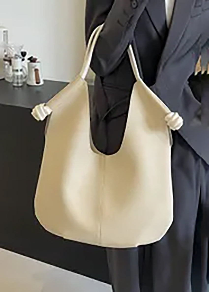 Light beige shoulder bag with a soft textured finish, featuring unique knotted straps. A chic and versatile accessory suitable for daily use