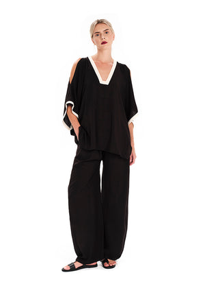 Woman wearing a black outfit with white trim on a white background