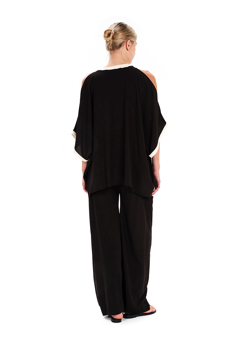 Woman wearing a black off-shoulder top and wide-leg pants on a white background