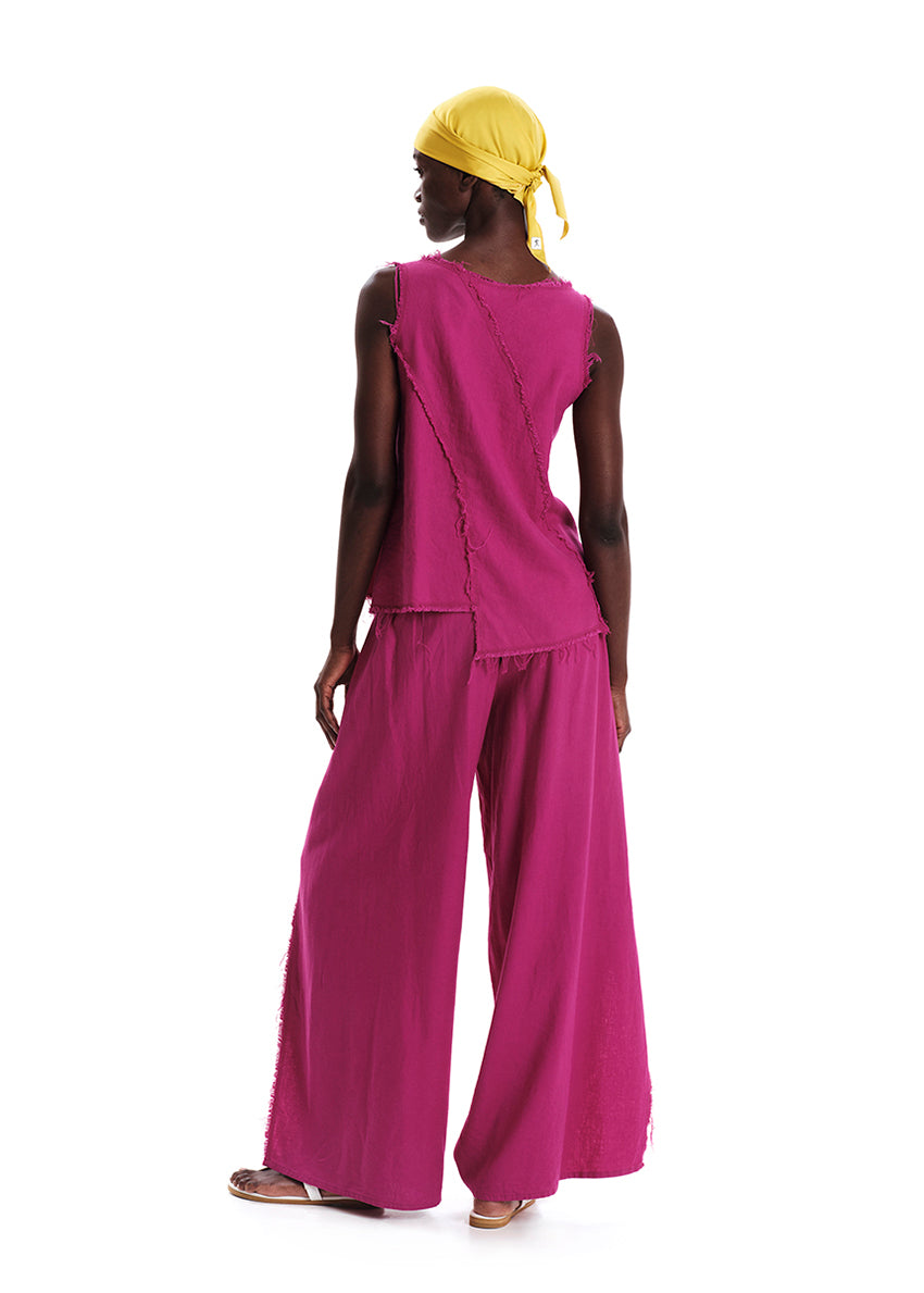 A model wearing a fringed linen top in magenta color with matching pants, paired with a yellow headwrap.