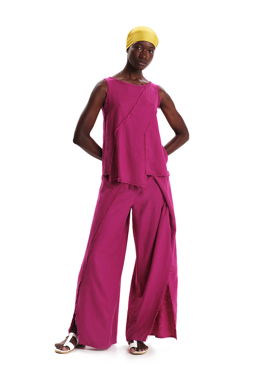 A model wearing a fringed linen top in magenta color with matching pants, paired with a yellow headwrap.