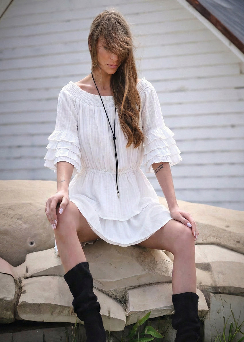 Woman in a white dress sitting on stone steps outdoors