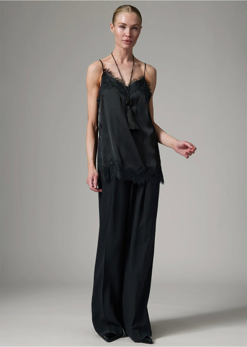 Woman wearing a black lace top and black pants on a gray background