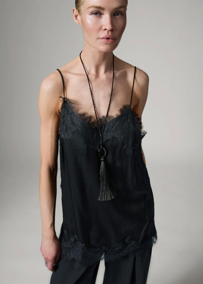 Woman wearing a black lace-trimmed top with a plain background