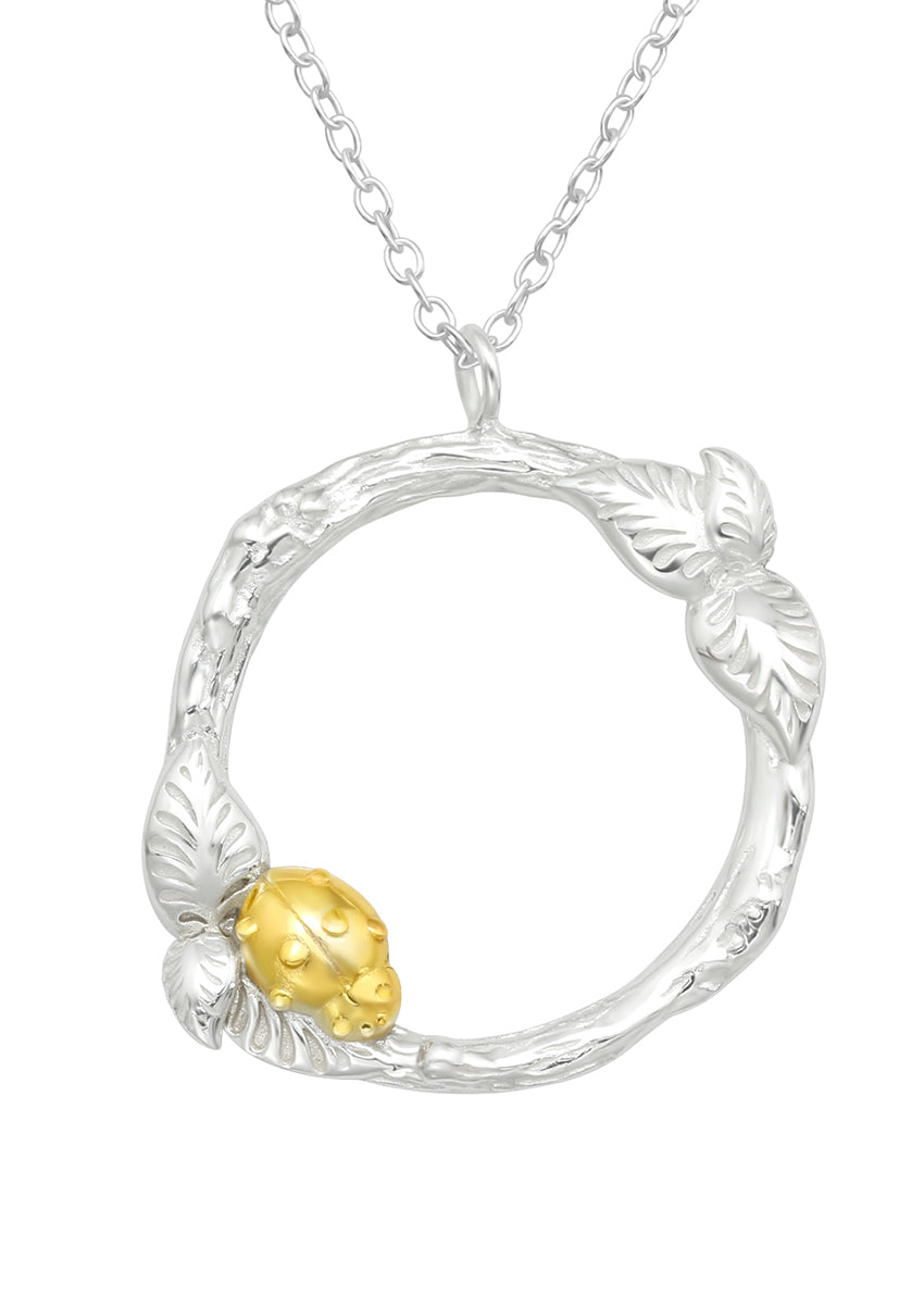 A silver necklace featuring a gold-colored ladybug design with leaf-shaped accents.