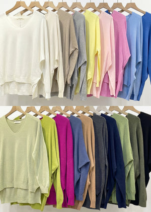 Row of colorful sweaters on hangers against a white background