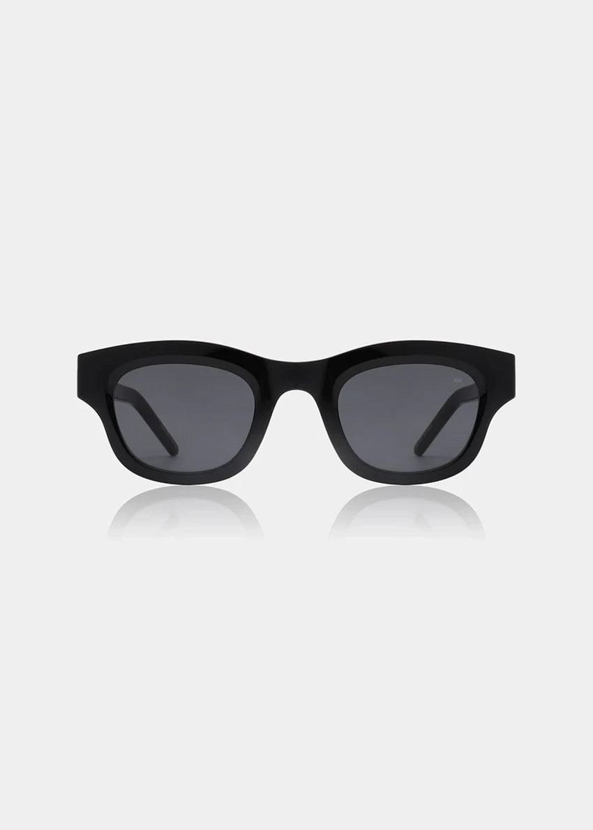Person wearing black sunglasses and a black outfit against a plain background