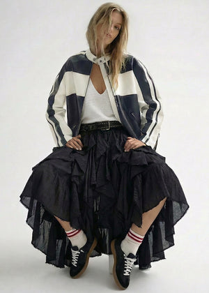 A stylish, contemporary outfit featuring a lightweight black-and-white jacket layered over a relaxed white top. The look is completed with a flowing black skirt, sporty socks, and lace-up shoes, creating a perfect blend of casual and edgy elegance.