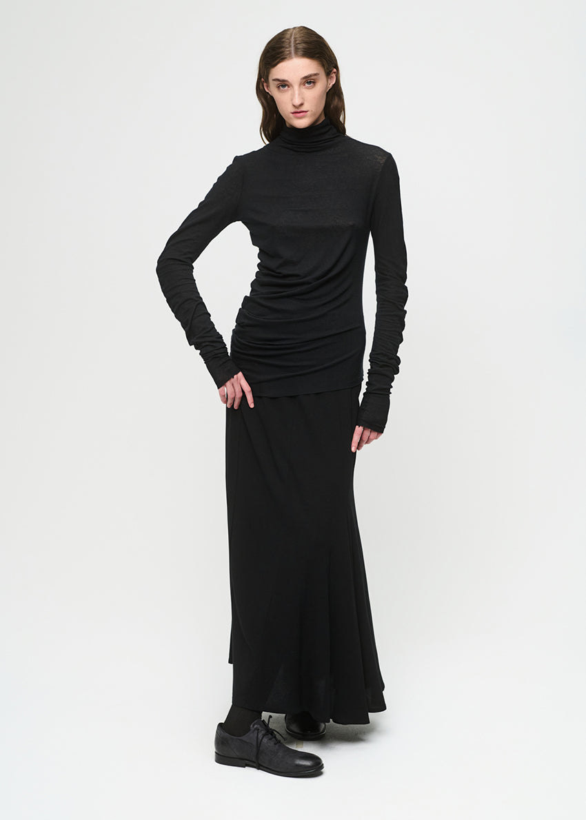Woman wearing a black turtleneck top with a black skirt on a white background