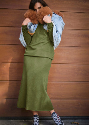 A person wearing a jeans jacket with dark olive green sweater and skirt 