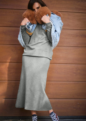 A person wearing a jeans jacket with grey sweater and skirt