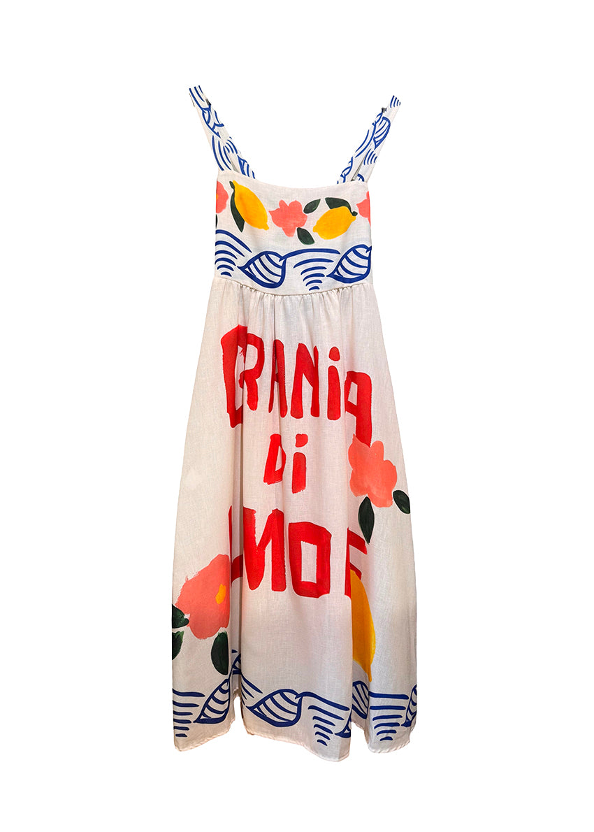 Woman wearing a colorful dress with floral and fruit patterns on a white background