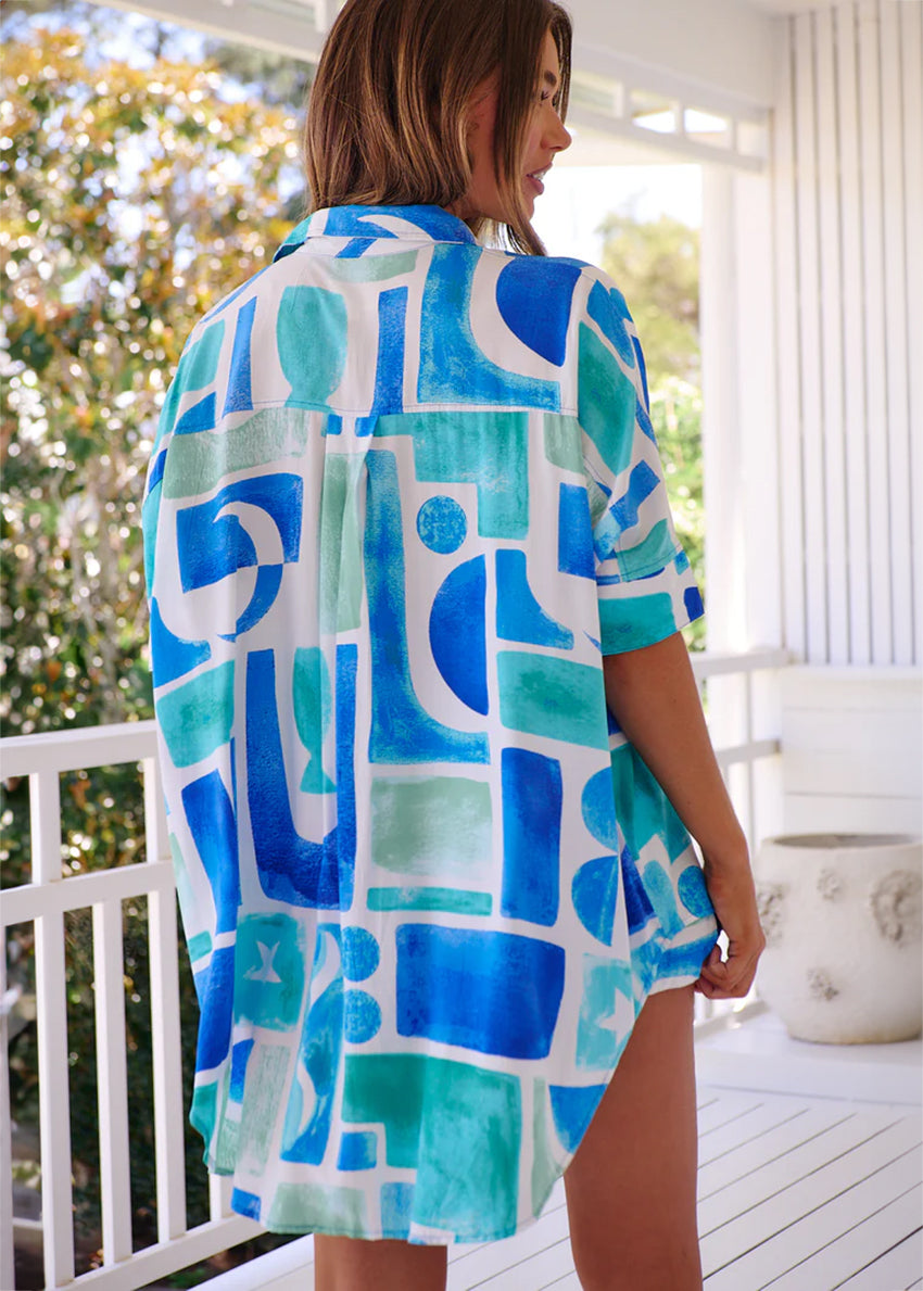 This shirt features a boyfriend-cut shirt which combines an oversized fit with a mediteranean flair, making it a versatile addition to any outfit. Its design includes a collar detail and long sleeves with oversized cuffs, allowing for effortless styling
