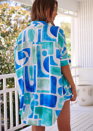 This shirt features a boyfriend-cut shirt which combines an oversized fit with a mediteranean flair, making it a versatile addition to any outfit. Its design includes a collar detail and long sleeves with oversized cuffs, allowing for effortless styling